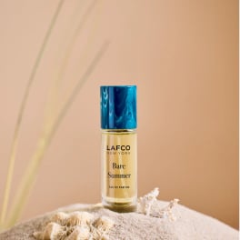 Bottle of LAFCO New York Bare Summer perfume on sand with seashells