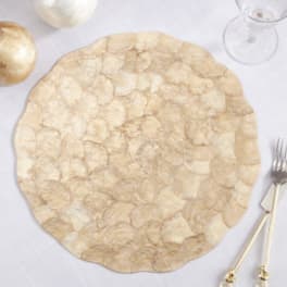 Round gold-toned charger plate on a white table setting