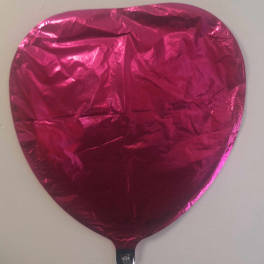 Pink heart-shaped foil balloon on a plain background