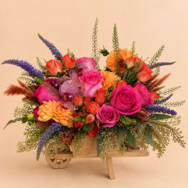 Bright mixed bouquet in a wooden wheelbarrow container