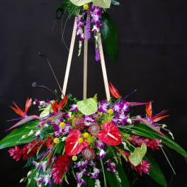 Tall tropical floral standing arrangement on an easel with purple, red, and white blooms