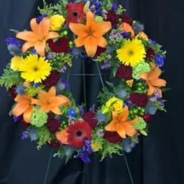 Colorful floral wreath on a stand with orange lilies and yellow daisies