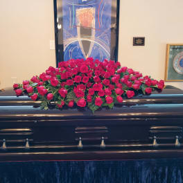 Pink rose casket spray on a dark casket