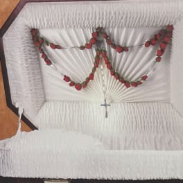 White casket with red rose garland and a small cross