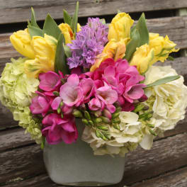 Colorful bouquet of tulips, hyacinth, and hydrangeas in a gray vase
