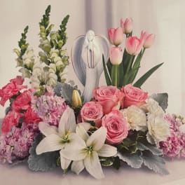 Pink roses, white lilies, and tulips arranged around a figurine