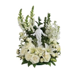 White floral arrangement with a small religious statue in the center