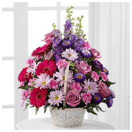 Pink and purple mixed flower arrangement in a white basket