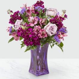 Purple and pink mixed bouquet in a purple glass vase