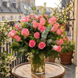 Pink roses arranged in a clear glass vase with greenery