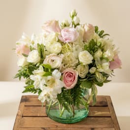 Pink and white flower arrangement in a green glass vase