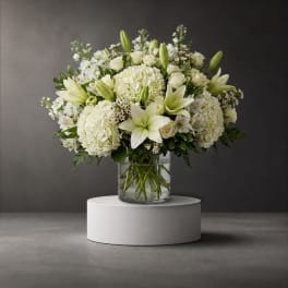 White floral arrangement in a clear glass vase on a pedestal