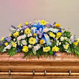 Large floral casket spray with yellow, white, and purple flowers