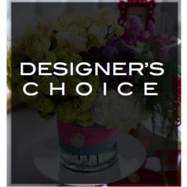 Mixed flower arrangement in a glass vase with a designer's choice label