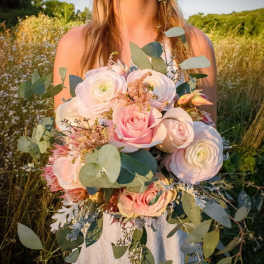 Bride holding a pastel bouquet of roses and ranunculus with eucalyptus
