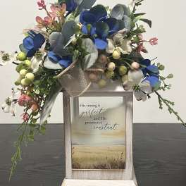 Floral arrangement with blue and white blooms in a rustic wooden frame sign