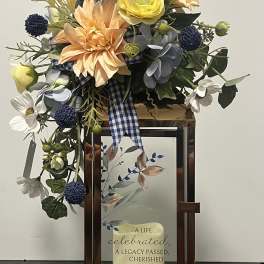 Mixed floral arrangement in a lantern-style frame with a memorial plaque