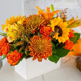 Orange and yellow flower arrangement in a white box