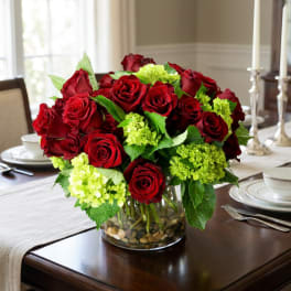 Red roses and lime-green hydrangeas in a clear glass vase