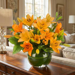 Orange lilies arranged in a round glass vase