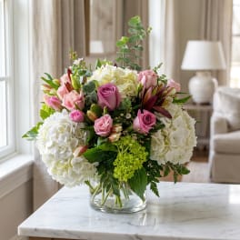 Pink roses and white hydrangeas in a clear glass vase