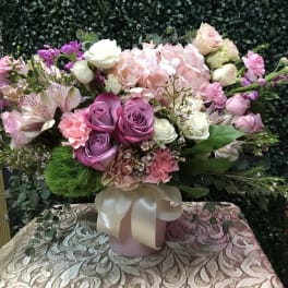 Pink and purple mixed flower arrangement in a ribbon-tied vase