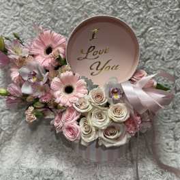 Pink and white flower arrangement in a round box with a "I Love You" lid