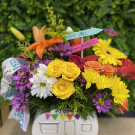 Colorful bouquet in a camper-shaped container with small sign picks