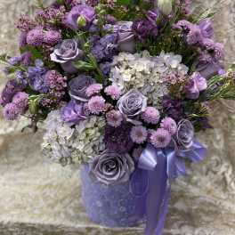 Lavender and purple bouquet with roses, hydrangeas, and ribbon in a purple vase