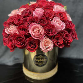 Bouquet of red and pink roses in a gold hat box