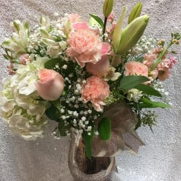 Pastel bouquet of lilies, carnations, roses, and hydrangea in a glass vase