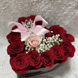 Heart-shaped box of red roses with a pink rose and ribbon bow