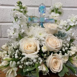 White floral arrangement with cream roses and a crystal cross topper