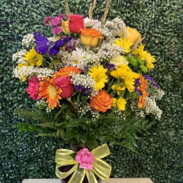 Mixed bouquet in a dark vase with a yellow ribbon