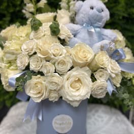 Cream rose bouquet with a blue teddy bear in a pastel box