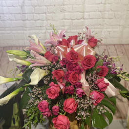 Pink roses and lilies arranged with a satin bow.
