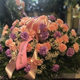 Large floral arrangement of pink and purple carnations with a satin ribbon