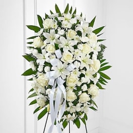 White funeral spray with lilies and roses on a standing easel
