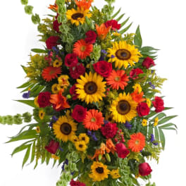 Tall standing spray of sunflowers, roses, and orange blooms
