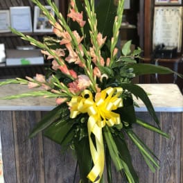 Tall floral spray with peach gladiolus and a yellow ribbon