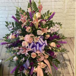 Large standing floral spray with pink lilies, roses, and purple accents