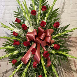 Standing floral spray of red roses with a large pink ribbon