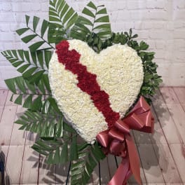 Heart-shaped floral tribute with a red diagonal stripe and pink ribbon