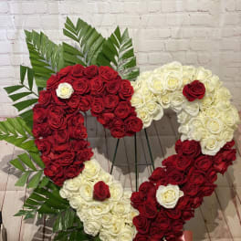 Heart-shaped arrangement of red and white roses with palm leaves