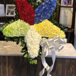 Cross-shaped floral tribute with red, blue, yellow, green, and white flowers
