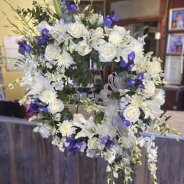 White floral wreath with blue accents and a sheer ribbon