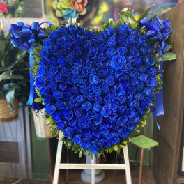 Heart-shaped arrangement of blue roses with ribbon bows on an easel