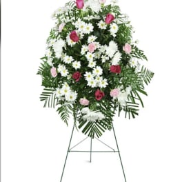 Standing floral spray with pink roses, white daisies, and greenery on an easel