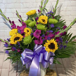 Bright mixed bouquet with sunflowers, purple flowers, and a lavender ribbon