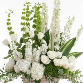 White floral arrangement in a pale basket with tall green and white spikes